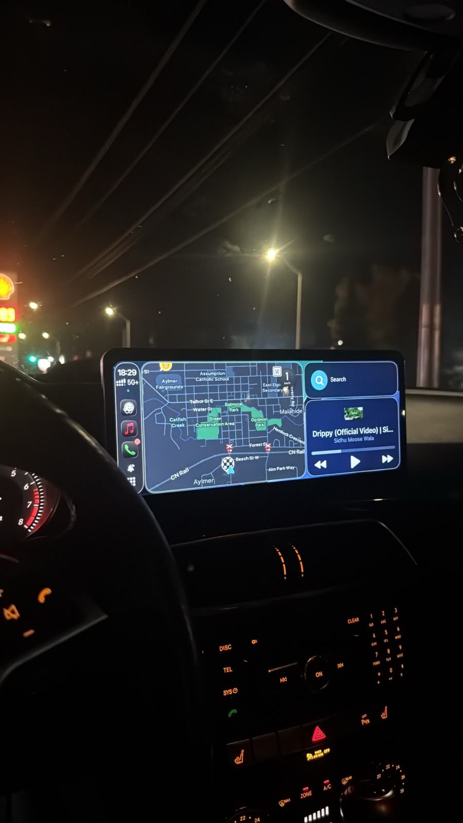 Widescreen Apple CarPlay head unit running maps and music in a Mercedes