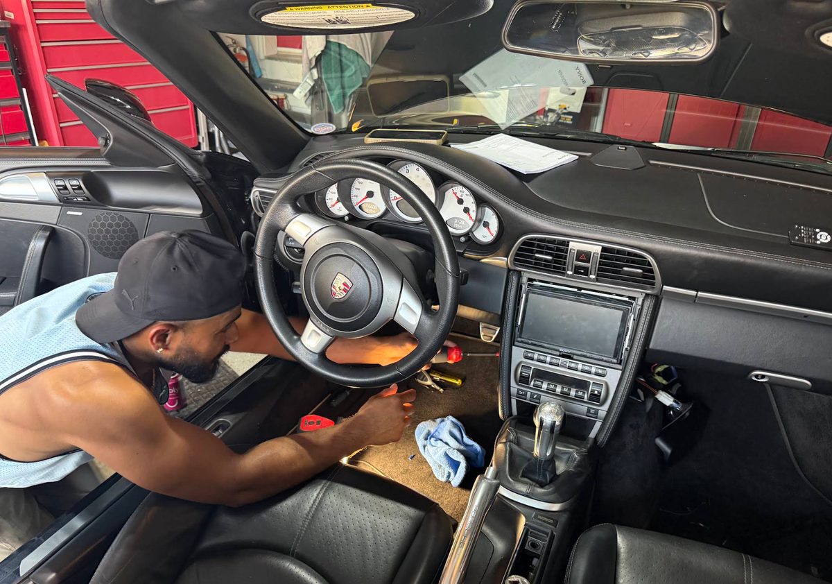 Technician fitting a new head unit in a Porsche 911 at the shop